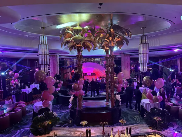 Gold palm trees and pink balloon columns at an evening ballroom gala