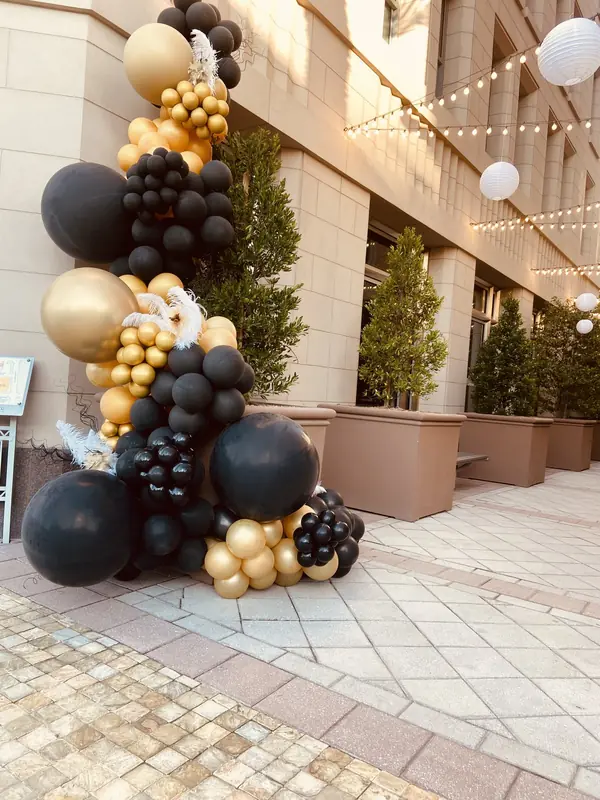 Black, gold and white balloon columns outside an event venue