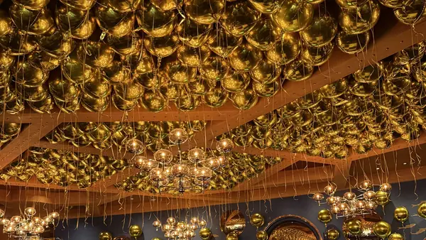 A ceiling filled with hundreds of gold balloons above a ballroom