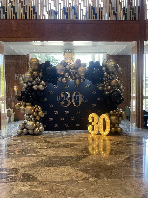 Balloon arch and custom backdrop in a marble hotel lobby