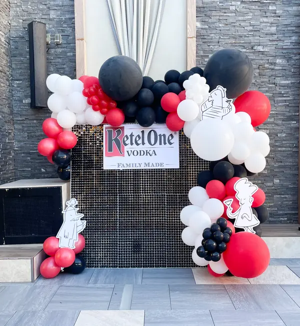 Red, black and white balloon arch around a sequin wall for a branded vodka event