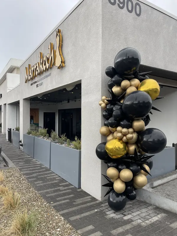 Black and gold balloon column at a restaurant storefront