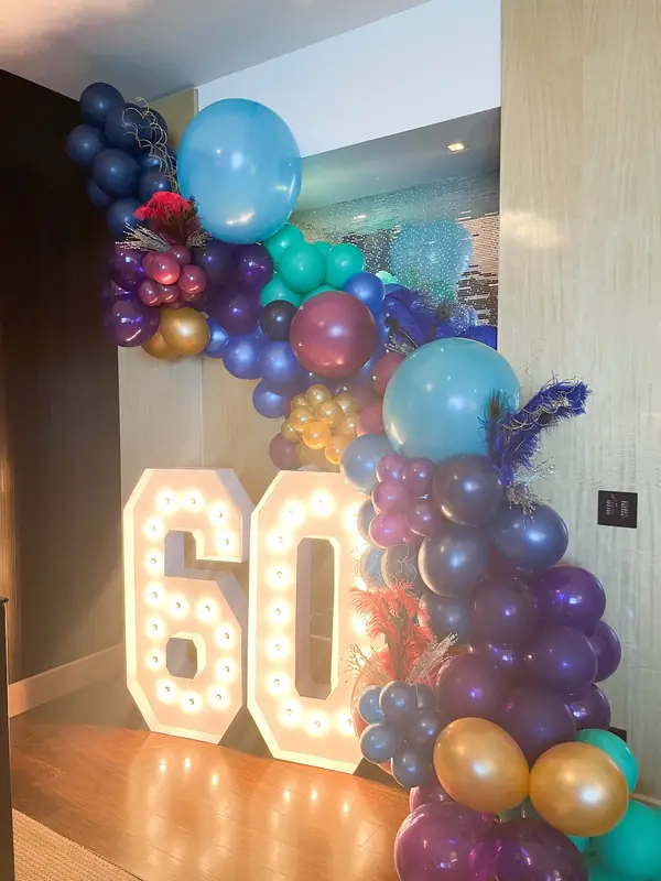 Lighted 60 marquee numbers wrapped in a jewel-tone balloon garland