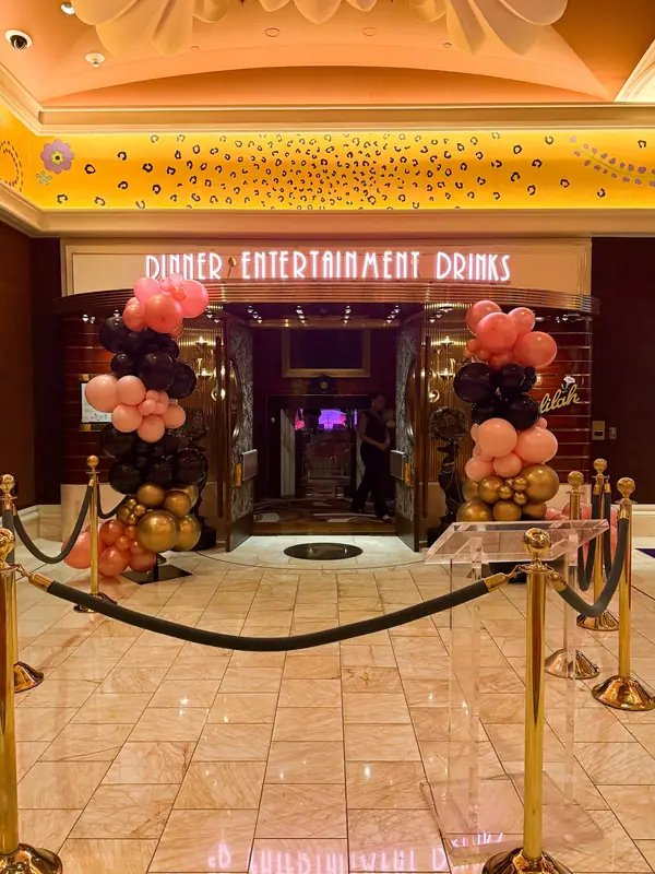 Pink, black and gold balloon columns framing a venue entrance